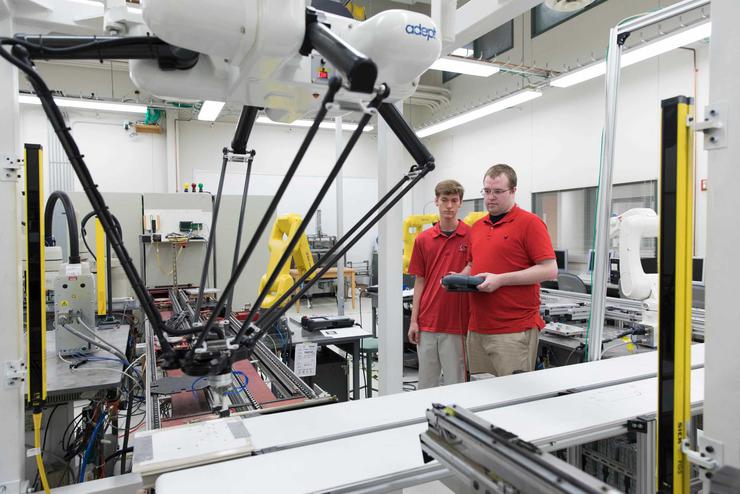 Two students work with machinery in an engineering lab.
