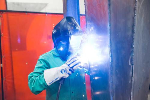 A student uses a welding torch while wearing a welding mask and protective gear. 