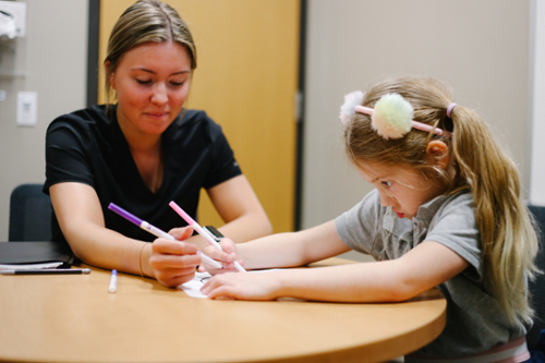 A semo student coloring with a little girl.