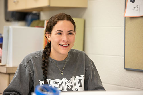 an interior design student in school in missouri at SEMO looks past the camera towards her classmate during a workshop for class.