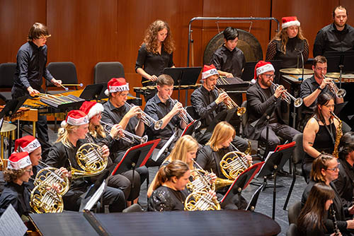 SEMO jazz students perform on stage with their instruments, most wearing holiday Santa hats