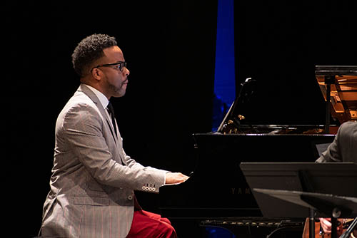a bachelor of arts in music major is seated at a piano and performing on stage for an audience