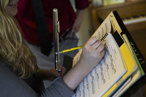 a music degree student makes notes on her music book while she practices