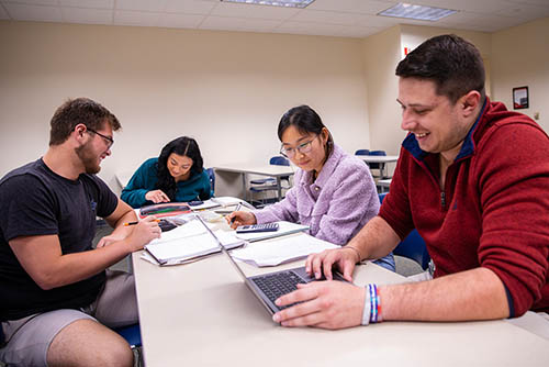 a group of students are gathered around a table working on an assignment for their accounting bachelors degree class