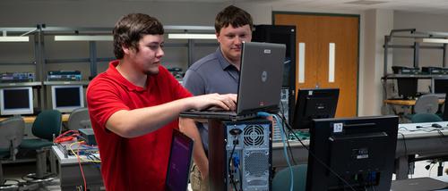 two electrical automation degree students work on a project on a lab computer. 