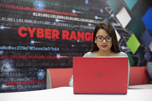 a cybersecurity major student sits in the cyber range and works on her computer