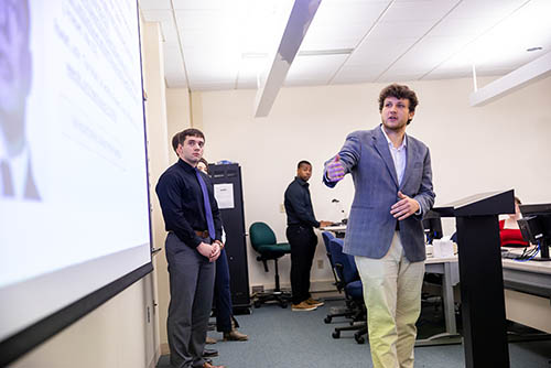 an organizational communication degree student stands at the front of a class and gives a presentation