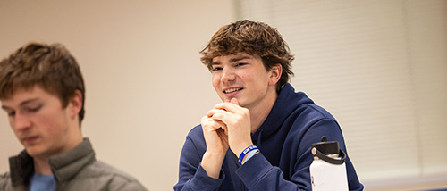marketing communications degree student smiles thoughtfully in class wearing a sorority jacket