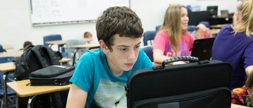 a junior high English student works on his computer intently in a classroom that semo's English language arts education major student teaches at