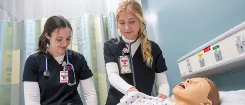 two students in the missouri nurse practitioner program at SEMO check a health studies mannequin's pulse in our innovative lab