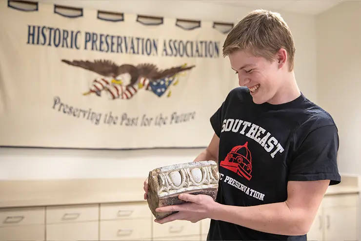A student in the Historic Preservation alumni chapter, an association for SEMO alumni, smiling at a piece of local history. 