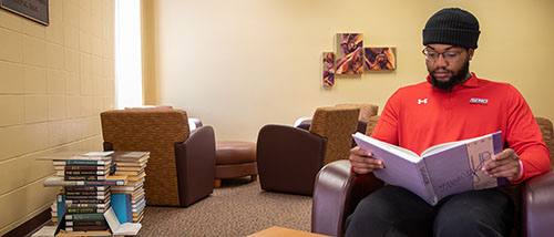 a student pursing a bachelor's degree in english sits in a chair reading a book