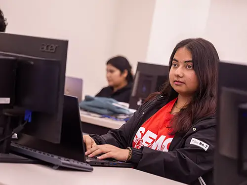 a computer science student works on her laptop in a computer lab