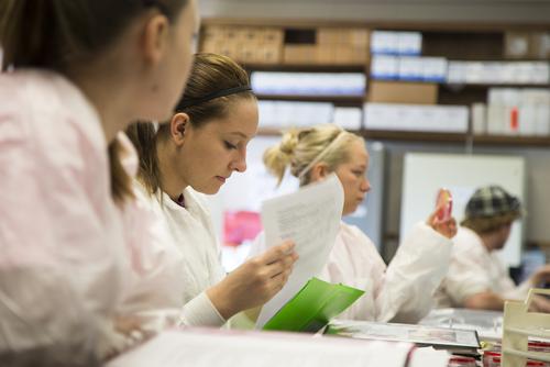 Students wearing white lab coats work on an assignment in class during a biology lab. 