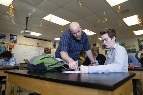 A biology student teacher helps a student with an assignment in class.