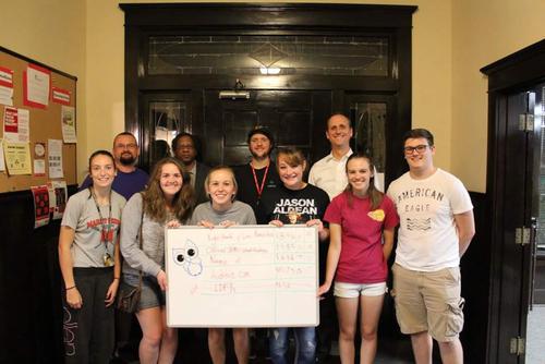 Sydney Bedillion stands with her class with a whiteboard showing results from their project. 