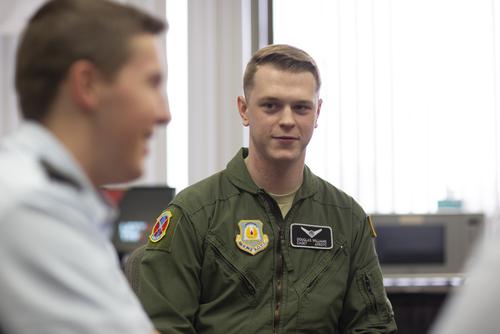 An Air Force ROTC cadet listens while sitting with fellow cadets.