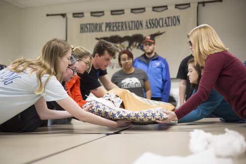 History majors work together to unfold a World War Two service banner from storage.
