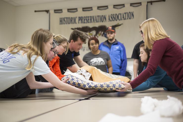 History majors work together to unfold a World War Two service banner from storage.