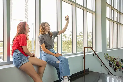 two semo students sit in the hallway in Dobbins and take a selfie