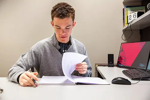 a semo student sits at a desk and flips through his notebook
