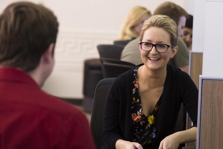 A woman, holding a calculator, meets with a learning assistant at Universal Tutorial Services. 