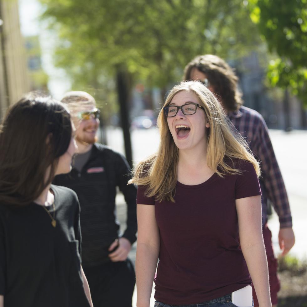 A student laughs while walking downtown with friends.