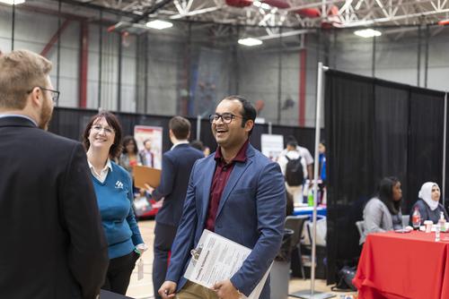 Southeast Missouri State University student networking and talking with employers at a campus career fair.