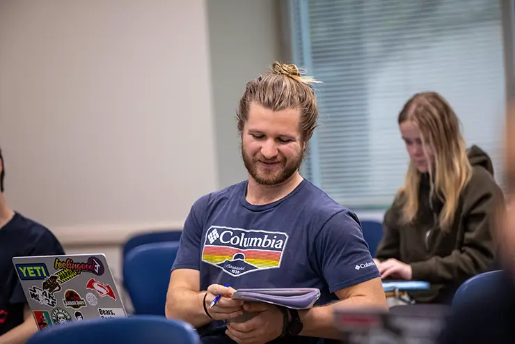 A student in class shares notes with a classmate