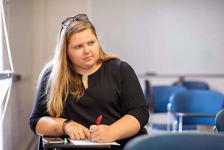 a SEMO student sits at a desk in a classroom with her notebook open taking notes