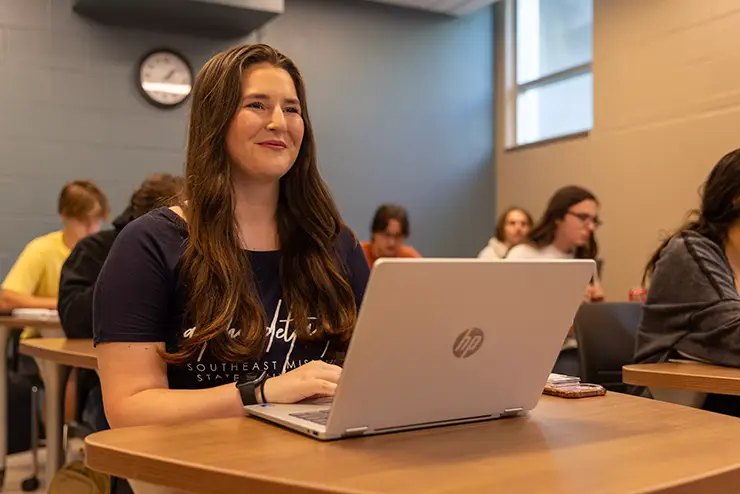 a SEMO student sits with her laptop in class watching the instructor