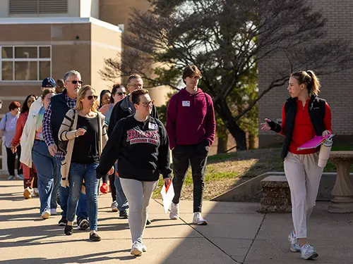 an Admission counselor leads a group of students and parents on a campus tour