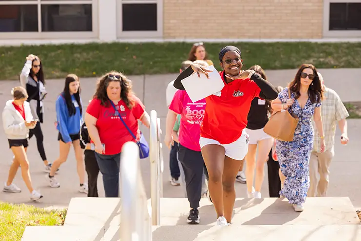 an admissions employee leads a group of students and parents on a walking tour