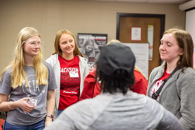 a group of high school students stand around in a group having a conversation