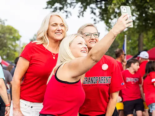 a student poses for a selfie with her family members at family weekend