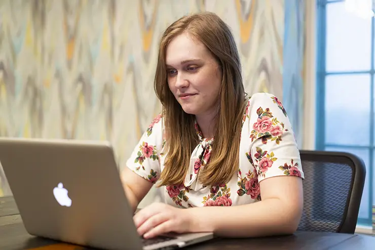 a SEMO online student sits at a table with her laptop open in front of her