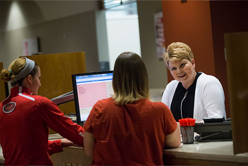 Two students at the desk of Student Financial Services working with someone.