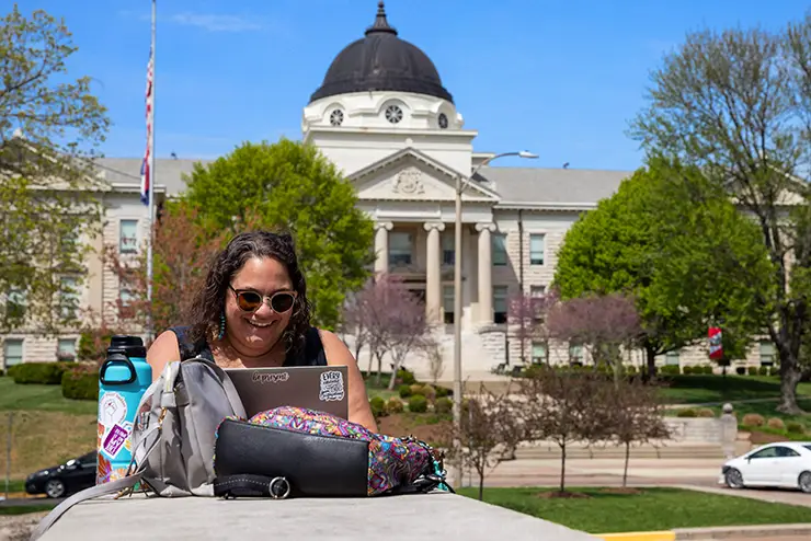 a SEMO student sits outside with academic hall in the background