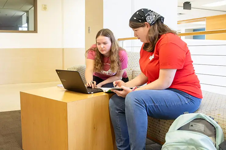 two SEMO students sit together in a common study area and review classwork