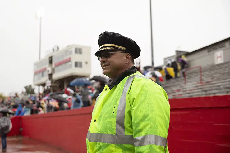 a university police officer stands watch in the rain at a football game