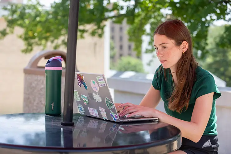 a SEMO grad student sits at a table outside and works on her laptop
