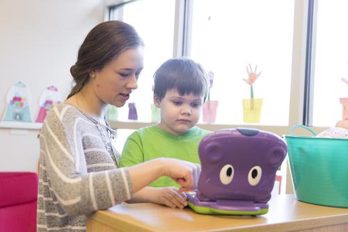 A staff member interacts with a child with a small toy in a classroom at the University Autism Center.