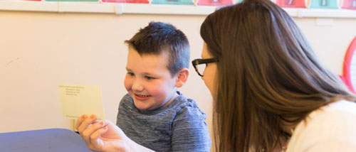 A staff member interacts with a child during a card exercise at the University Autism Center.