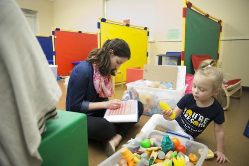 A child and two Autism Center staff members play a matching game at a table in a therapy room at the Center.