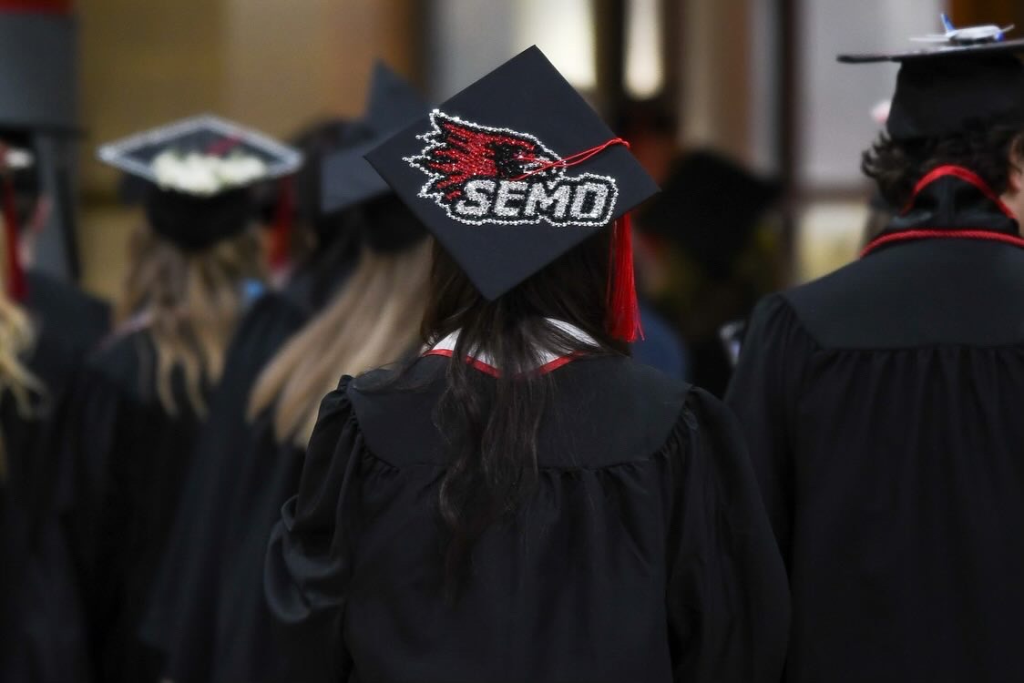 A SEMO graduate wearing a bejewled Redhawk on top of her graduation cap.