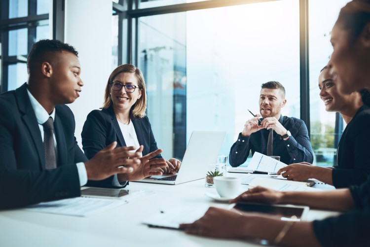 Business leaders meet around a conference table in a boardroom.