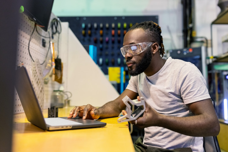 An applied technology professional sitting in front of a laptop in a technology lab.