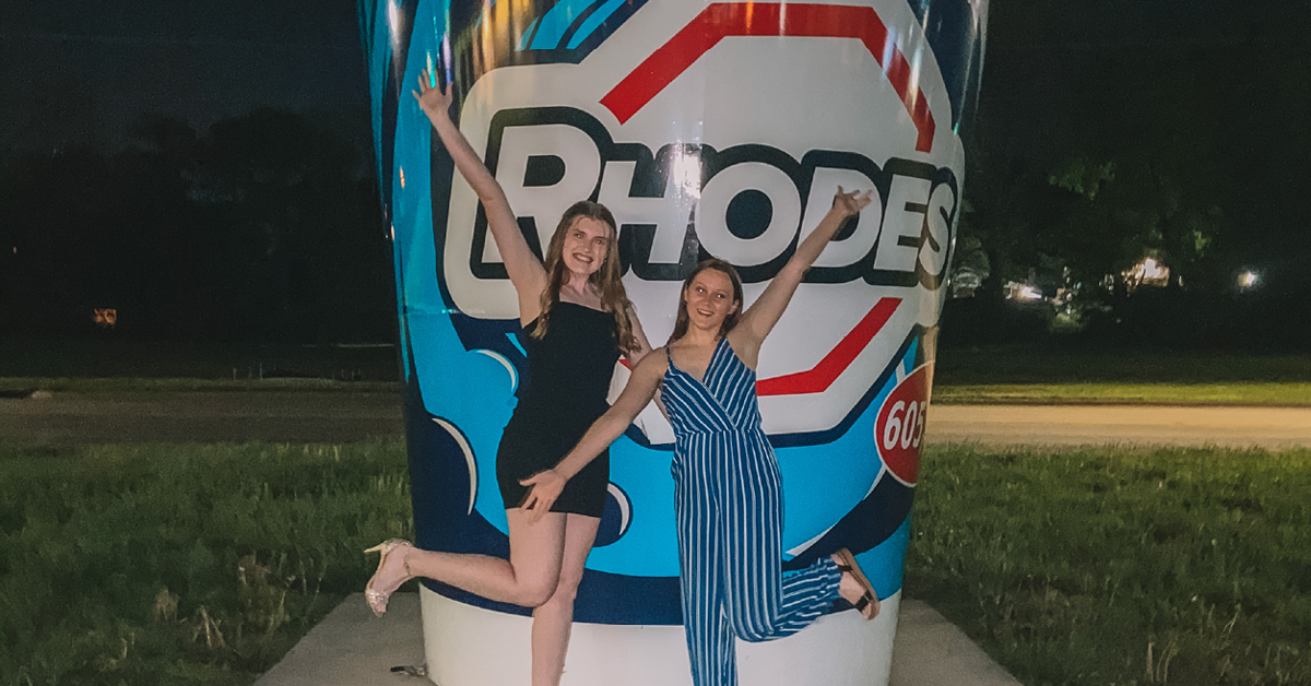 Two women pose with arms wide open in front of the World's largest Fountain Soda Cup