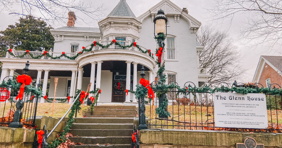 A large, white, Victorian style house decorated in garland