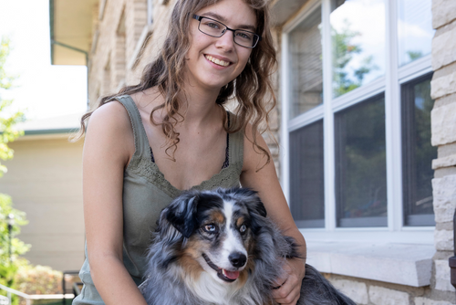A student and their dog sit for a photo near a SEMO Residence Hall.